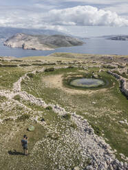 Aerial view of rocky coastline and small island with person, Baska Island, Croatia. - AAEF27866