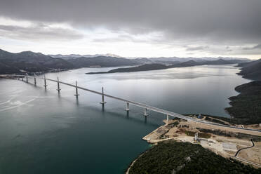 Aerial view of Peljeski Most, a long suspension bridge connecting the coast of Croatia, with clear blue waters and beautiful natural scenery. - AAEF27881