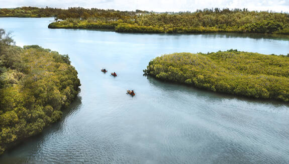 Luftaufnahme einer Drohne von drei Personen, die in orange-schwarzen Kanus in den Mangroven paddeln, Ilot Lievres, Flacq, Mauritius. - AAEF27920