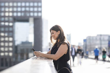 Lächelnde Frau mit Mobiltelefon in der Stadt - WPEF08571