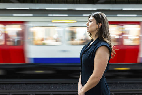 Young woman standing in front of moving subway train - WPEF08598