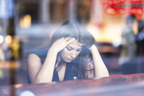 Frustrierte junge Frau sitzt in einem Cafe - WPEF08608