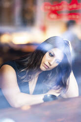 Stressed young woman seen through glass in cafe - WPEF08609