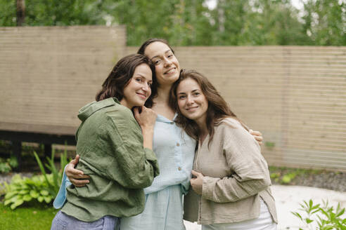 Smiling friends embracing together in back yard - SEAF02255