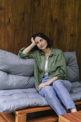 Nachdenkliche Frau sitzt zu Hause auf dem Sofa - SEAF02256