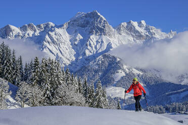 Frau beim Skifahren auf der Schwalbenwand mit Selbhorn in den Berchtesgadener Alpen, Dientener Berge, Salzburg, Österreich - ANSF00821