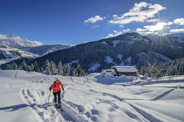 Frau beim Skifahren auf der Schwalbenwand mit Selbhorn in den Berchtesgadener Alpen, Dientener Berge, Salzburg, Österreich - ANSF00823