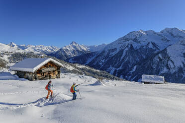 Älteres Paar beim Skifahren in der Nähe der Hütte am schneebedeckten Rastkogel an einem sonnigen Tag, Zillertaler Alpen, Tuxer Alpen, Tirol, Österreich - ANSF00843