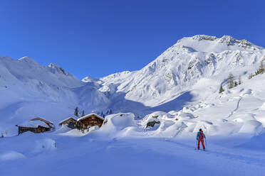 Frau beim Skifahren auf dem Weg zur Hütte unter Schnee am Junsjoch, Tuxer Alpen, Tirol, Österreich - ANSF00845