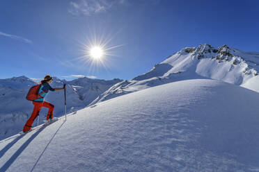 Woman back country skiing with backpack at Junsjoch with Pluderling in background, Tux Alps, Tyrol, Austria - ANSF00850