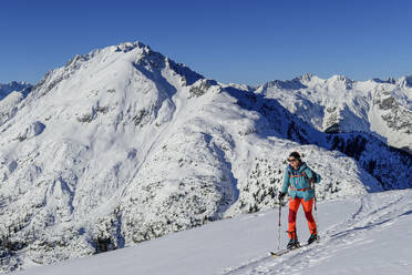 Ältere Frau beim Skifahren am Grünstein mit den Lechtaler Alpen im Hintergrund, Mieminggruppe, Tirol, Österreich - ANSF00853