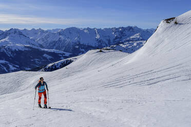 Ältere Frau beim Skifahren am Kastenwendenkopf mit Zillertaler Alpen im Hintergrund, Kitzbüheler Alpen, Tirol, Österreich - ANSF00861