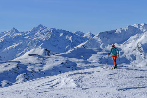 Ältere Frau beim Skifahren auf dem Kastenwendenkopf mit den Zillertaler Alpen im Hintergrund an einem sonnigen Tag, Kitzbüheler Alpen, Tirol, Österreich - ANSF00864