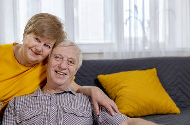 Smiling senior couple sitting at home - MBLF00290