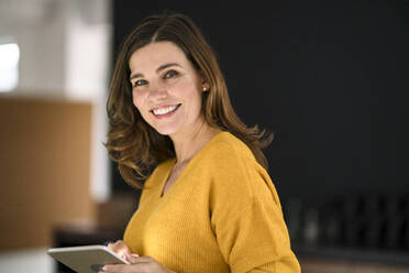 Smiling creative businesswoman with tablet PC in office - KNSF10069