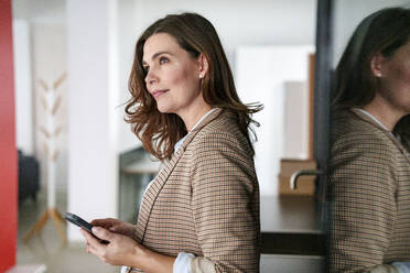 Thoughtful businesswoman near window in office - KNSF10094