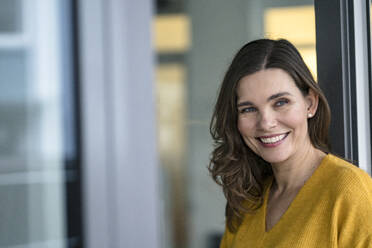 Smiling creative businesswoman near window in office - KNSF10126