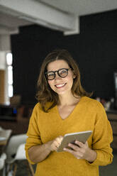 Lächelnde kreative Geschäftsfrau mit Tablet-PC im Büro - KNSF10131