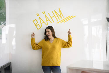 Kreative Geschäftsfrau, die auf einen Text vor einer weißen Wand mit Text im Büro zeigt - KNSF10156