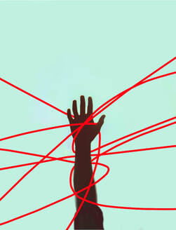 Hand einer nicht erkennbaren Person, die sich in roten Schnüren vor einem farbigen Hintergrund verheddert - GWAF00527