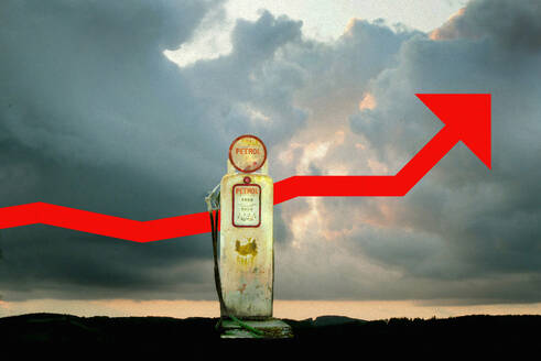 Rusty fuel pump in front of ascending red arrow under cloudy sky - GWAF00534