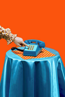 Hand of woman dialing on keypad of telephone against orange background - RDTF00074