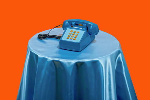 Vintage style telephone on table against orange background - RDTF00075