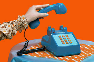 Hand of woman picking up telephone receiver against orange background - RDTF00079
