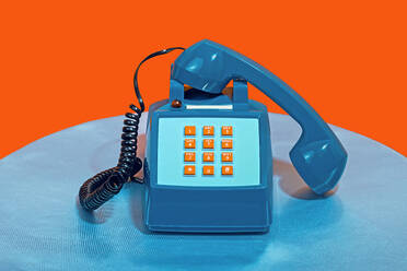 Retro style telephone on table against orange background - RDTF00080