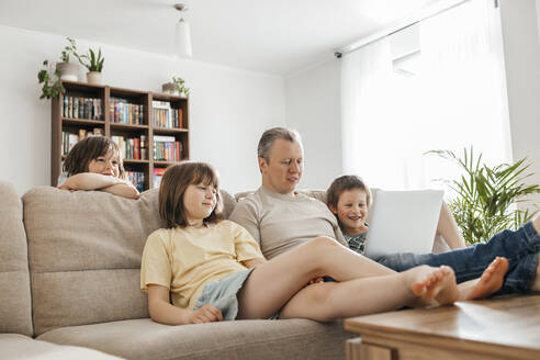 Father watching movie with children on laptop at home - ELMF00118