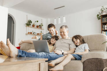 Happy family watching movie on laptop at home - ELMF00119