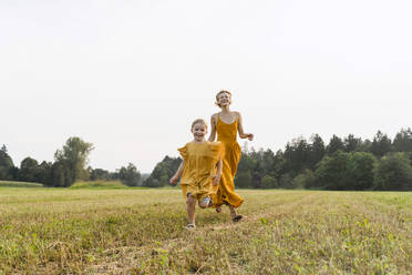 Playful mother and daughter running in meadow - NDEF01611