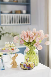 Osterdekoration und pfirsichfarbene Tulpen auf dem Tisch zu Hause - ONAF00726