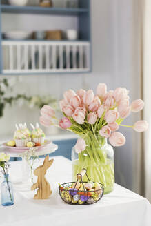 Easter decorations and peach color tulips on table at home - ONAF00726