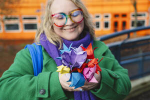 Lächelnde Frau hält bunte Origami-Blumen - IHF01899