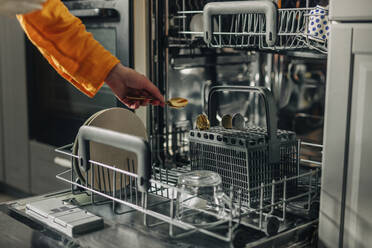 Hand of woman picking up spoon from dishwasher at home - VSNF01774