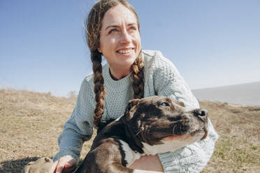 Glückliche Frau mit Hund auf einem Hügel an einem sonnigen Tag - KVBF00056