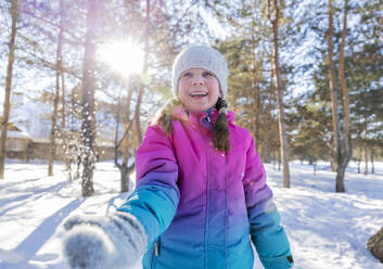 Glückliches Mädchen spielt mit Schnee im Winterwald an einem sonnigen Tag - MBLF00303