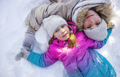 Mutter und Tochter im Schnee liegend im Winter - MBLF00307