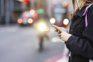 Frau hält Mobiltelefon auf der Straße - WPEF08678