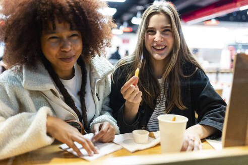 Smiling friends sitting with food in cafe - WPEF08686