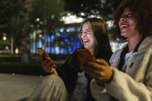 Happy young friends with mobile phones enjoying at night - WPEF08712