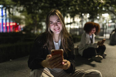 Happy beautiful woman with mobile phone at night - WPEF08721