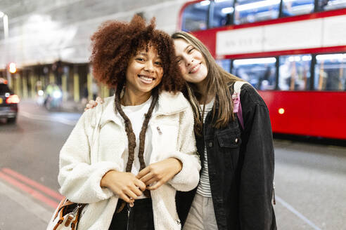 Happy young women standing together on street in city at night - WPEF08723