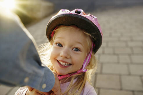 Happy girl wearing sports helmet on footpath - NSTF00049