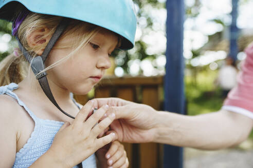 Vater hilft seiner Tochter, den Helm im Park zu befestigen - NSTF00072