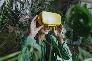 Smiling businesswoman wearing yellow virtual reality simulator - YTF02035