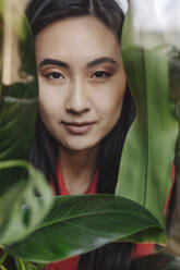 Smiling young woman near leaves - YTF02047