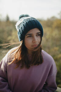 A young female with a contemplative gaze, wearing a beanie, surrounded by natural beauty on an Iceland trip. - ADSF53333