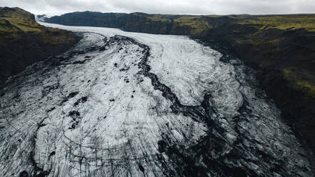 Aerial view capturing the intricate patterns of Vatnajokull Glacier, Iceland's largest and most voluminous ice cap, nestled between mountainous terrains. - ADSF53359